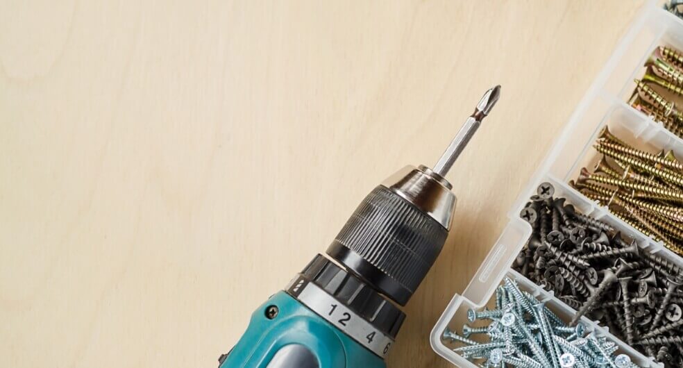 Wooden shelf with gray and olive drab green baseball caps, next to wooden clothes hanger with sweaters.